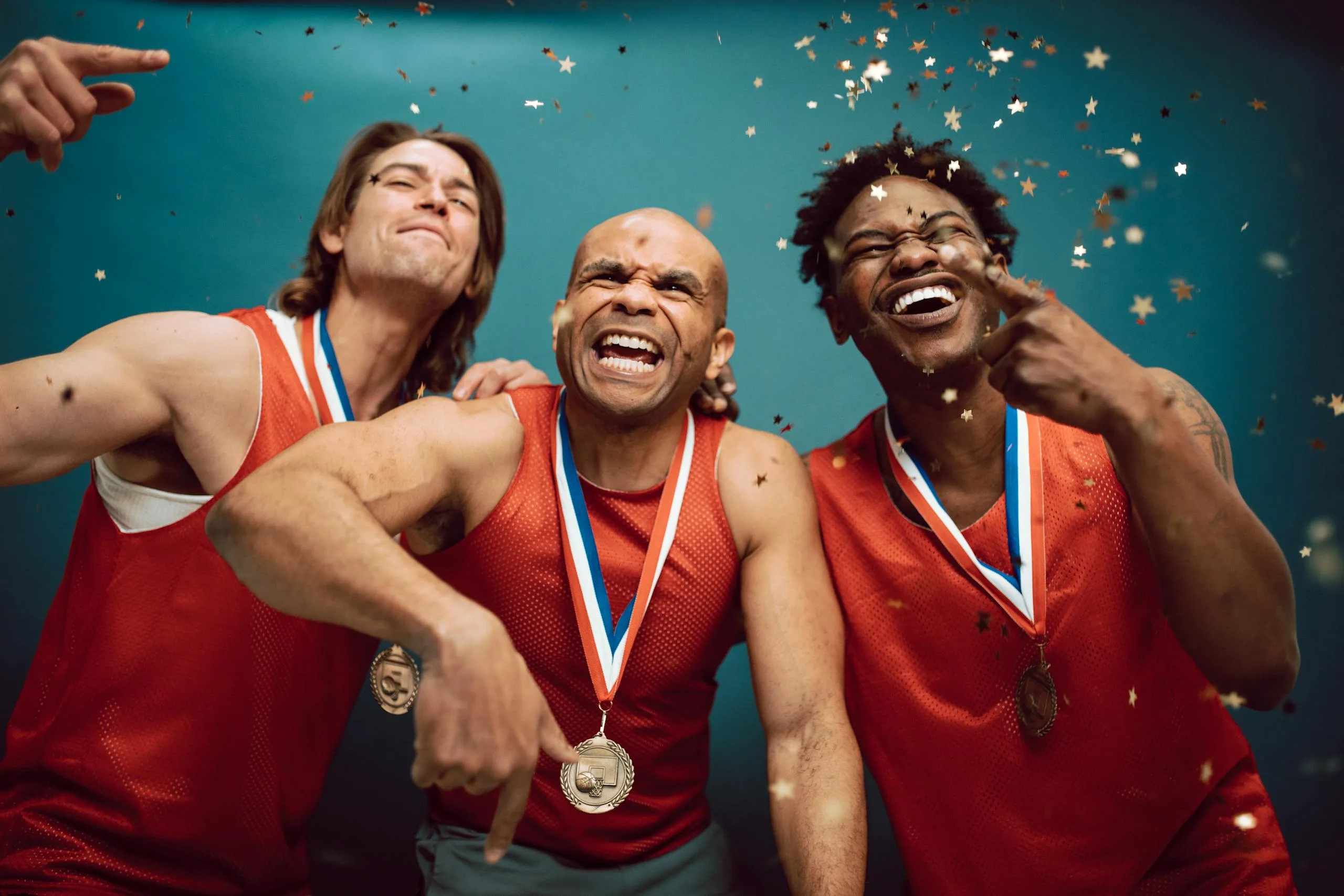 Three diverse athletes celebrate their victory with medals and confetti.